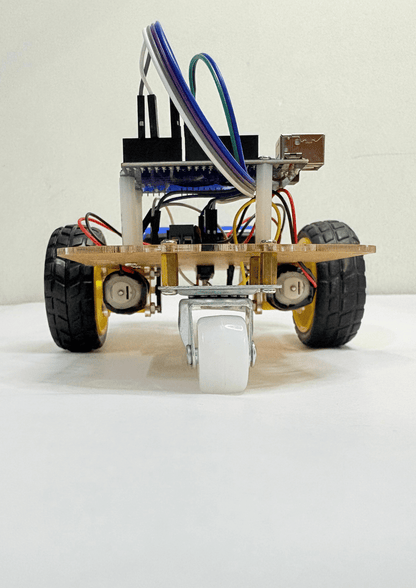 Front view of a two-wheeled Arduino robot car with caster wheel, motors, wiring, chassis board and jumper wires mounted on top.